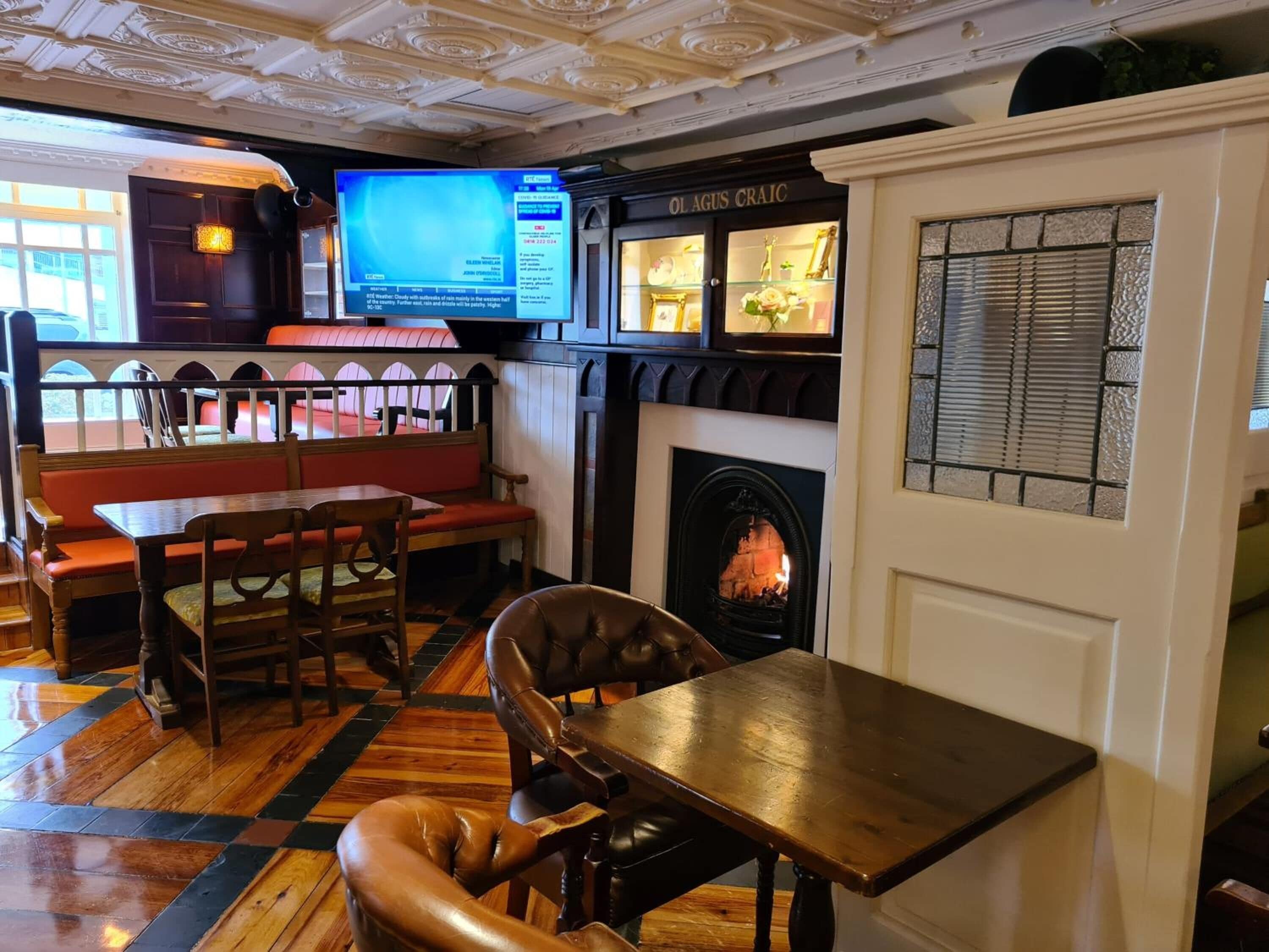 A cozy restaurant interior with a fireplace, wooden furniture, and a television screen.