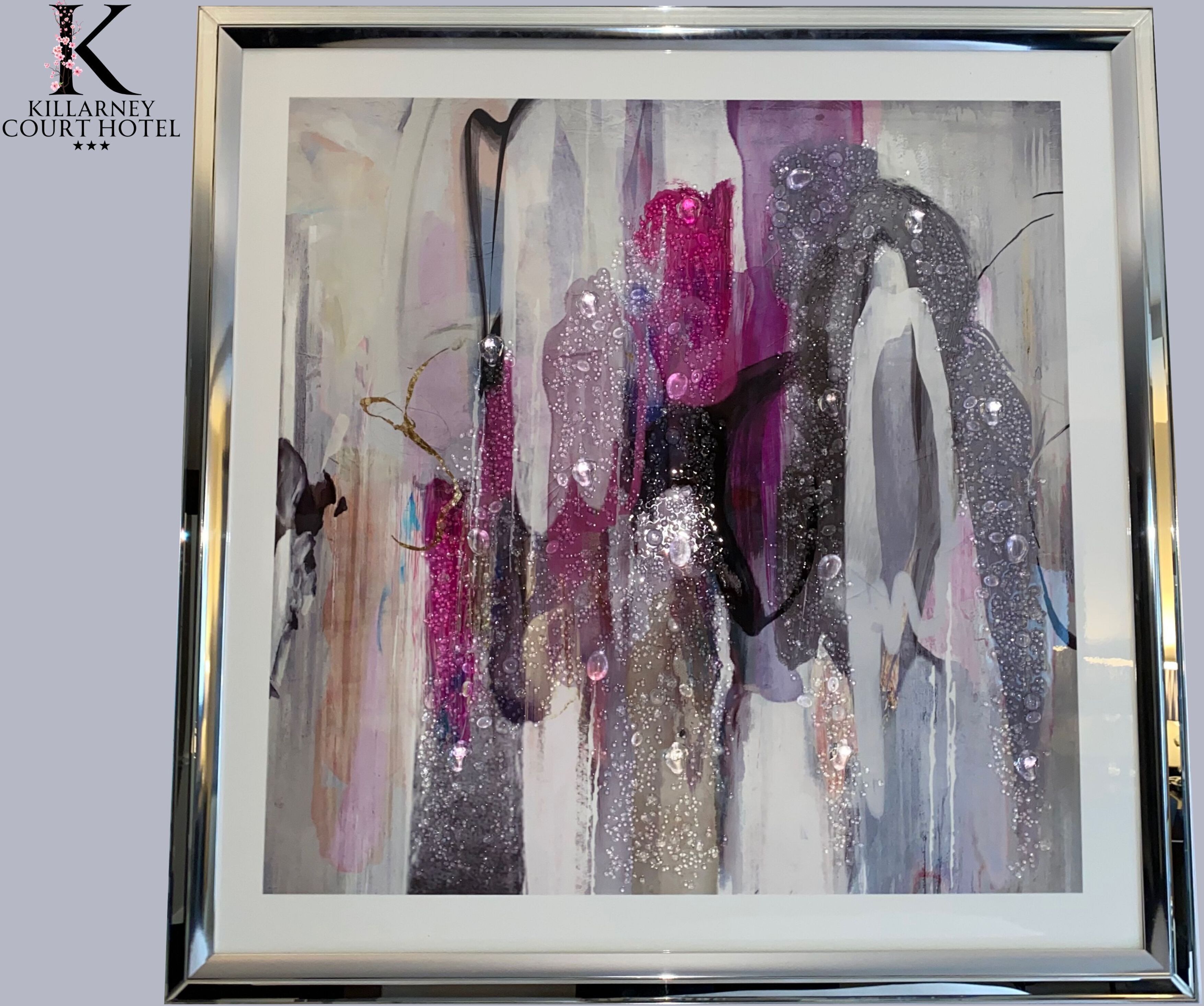 A framed abstract painting with a mix of colors and textures, including pink, purple, and silver tones.