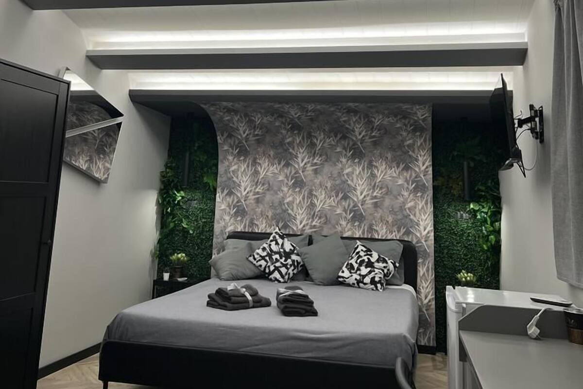 Un dormitorio moderno con cama, mesitas de noche, armario y televisor de pared.