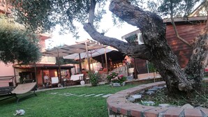 Un patio con mobiliario exterior, un muro de piedra y un árbol.
