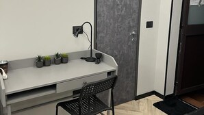 Una habitación pequeña con escritorio, silla y puerta.