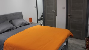 A bedroom with a bed, a nightstand, a mirror, and a door. - Townhouse @ 282 Walthall Street Crewe (Crewe)