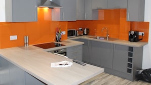 A modern kitchen with grey cabinets, an orange backsplash, and a wooden countertop. - Townhouse @ 282 Walthall Street Crewe (Crewe)