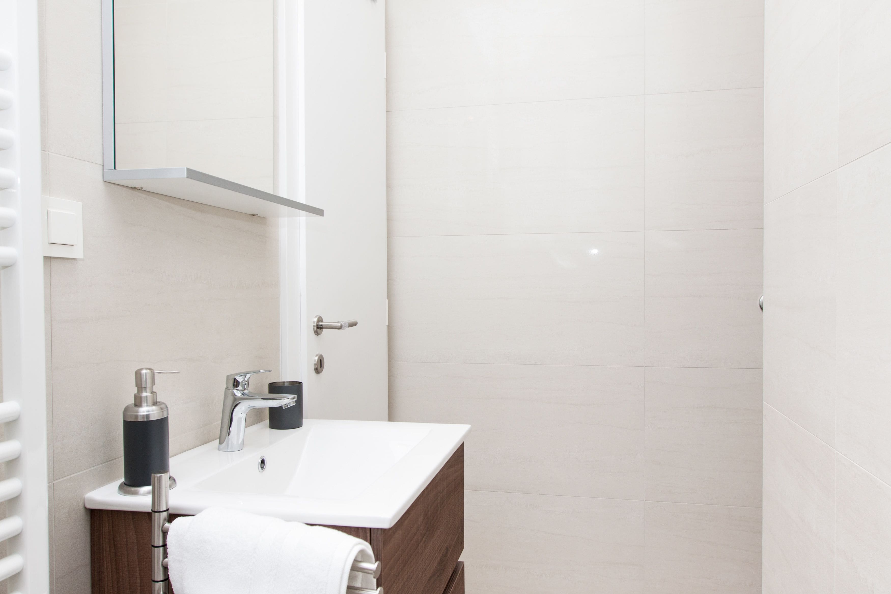 Een moderne badkamer met een witte wastafel, een spiegel en een handdoekhouder.