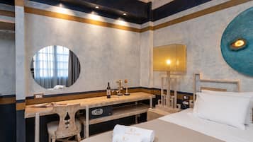 Una habitación de hotel con una cama, un escritorio con una silla, un espejo redondo, una lámpara de pared y un adorno circular grande en la pared.