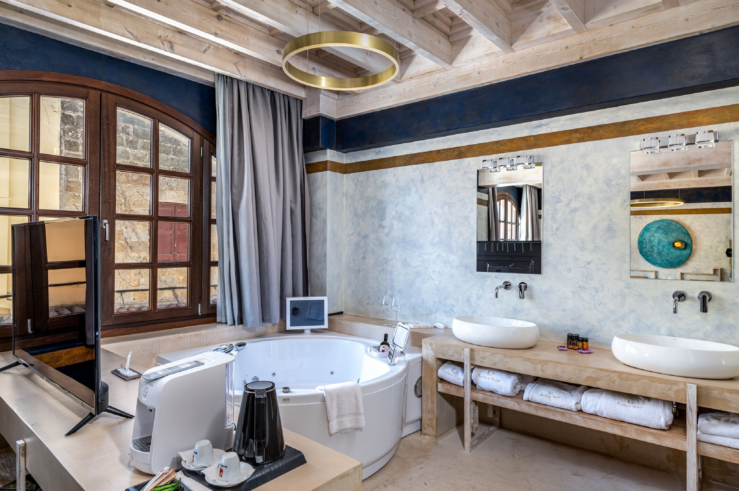 Ein modernes Badezimmer mit einer freistehenden Badewanne, zwei Waschbecken, einem großen Spiegel und einer Holzausstattung.