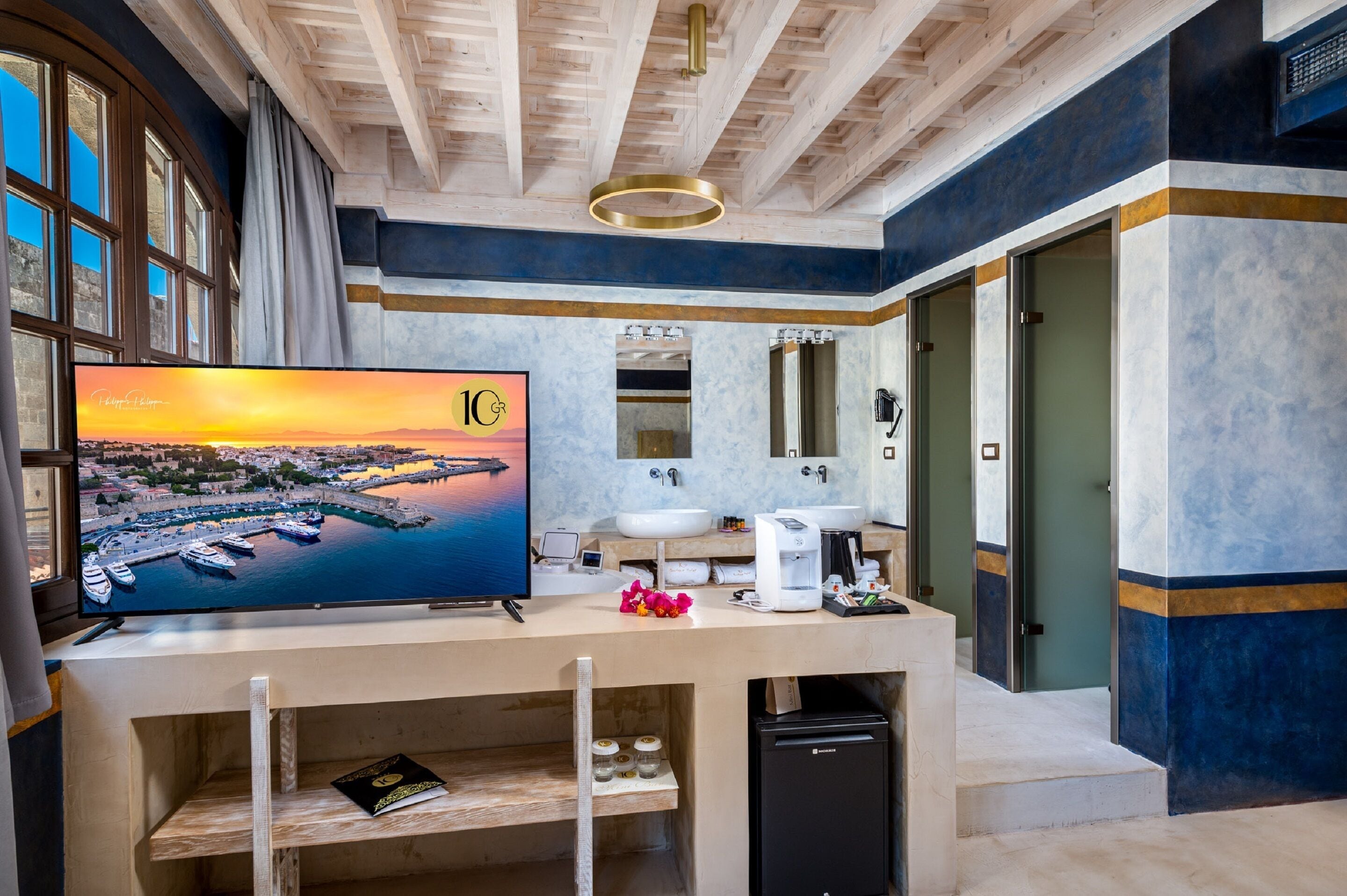 Un baño moderno con una televisión grande, un lavamanos y un espejo.