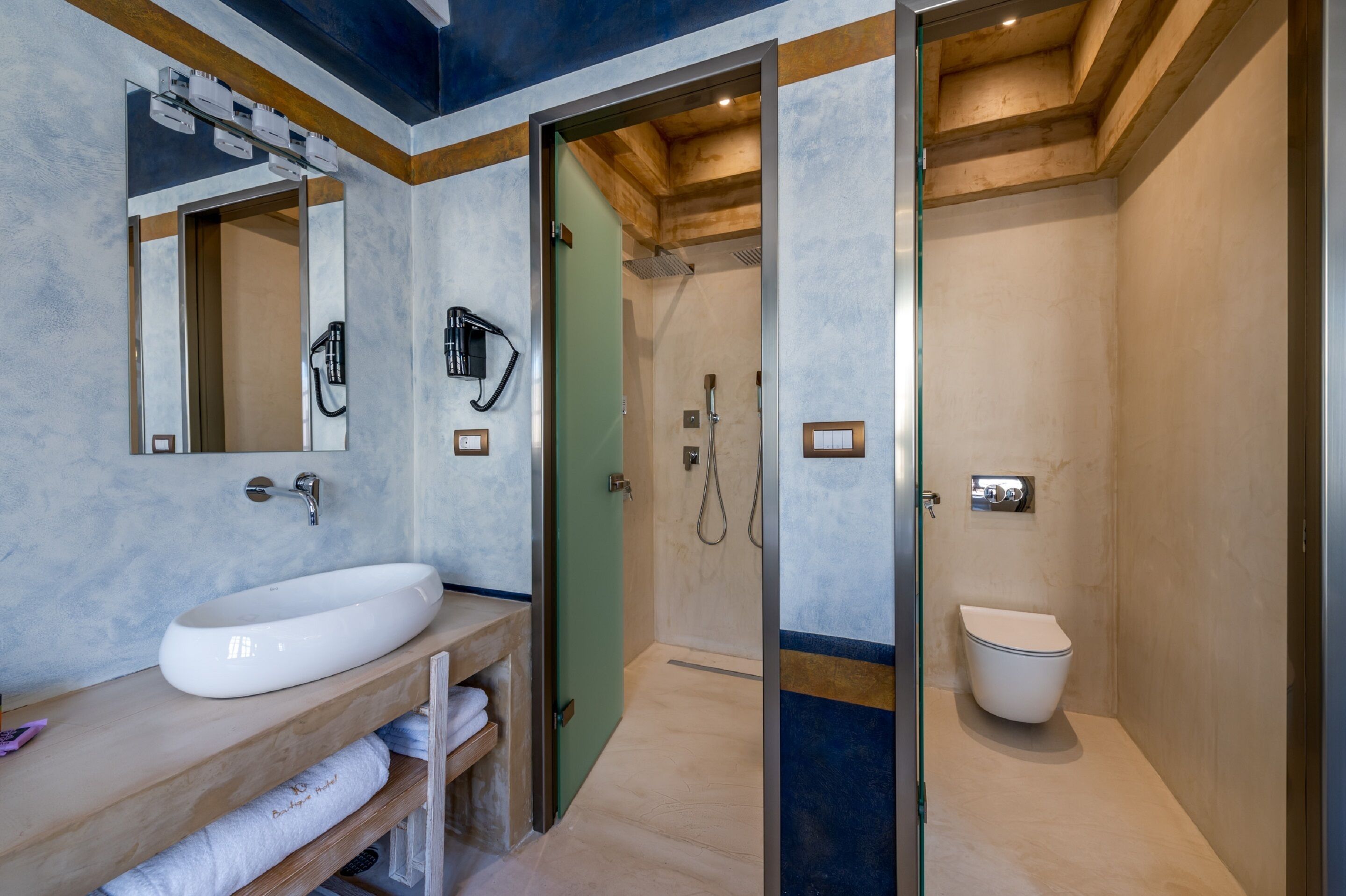 A modern bathroom with a large white sink, a mirror, a shower area, and a toilet.