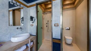 A modern bathroom with a large white sink, a mirror, a shower area, and a toilet.