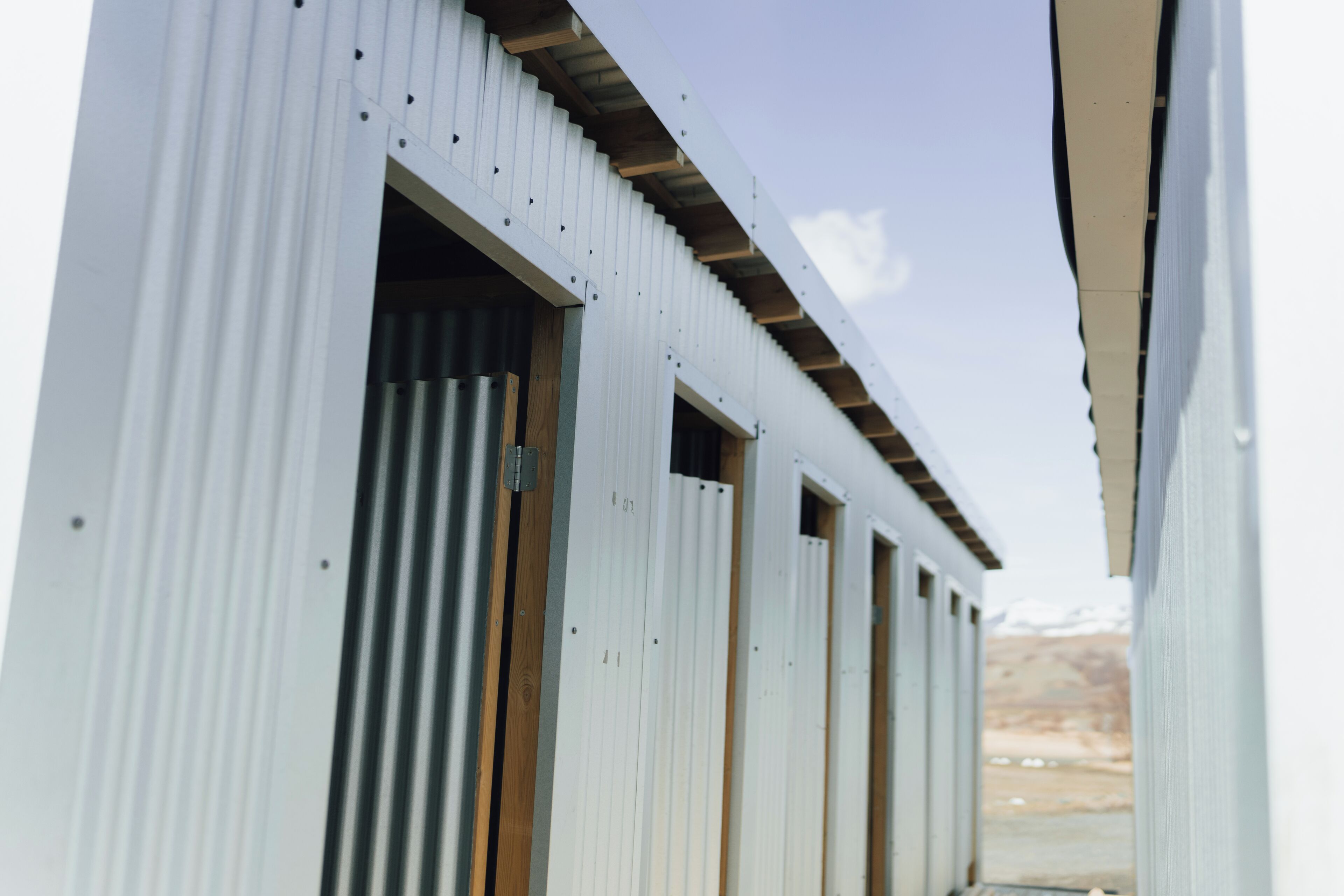 A row of white buildings with multiple doors and windows, suggesting a row of rooms or units.