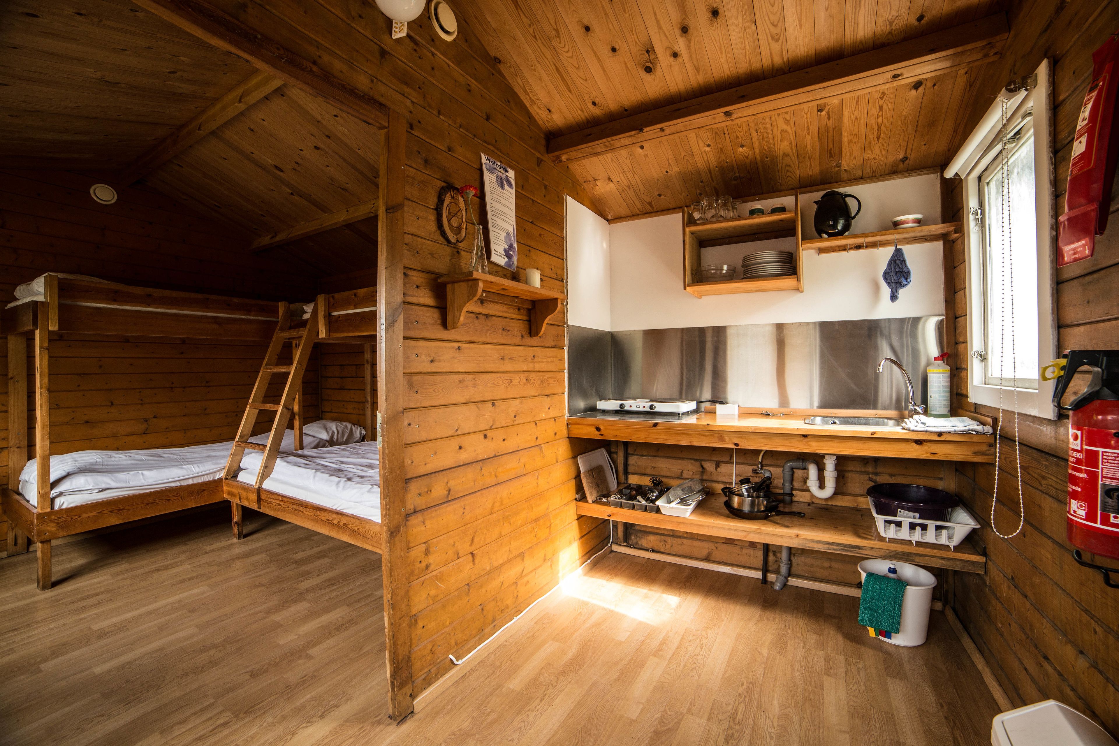 A cabin with two bunk beds, a kitchenette, and a window with a view.