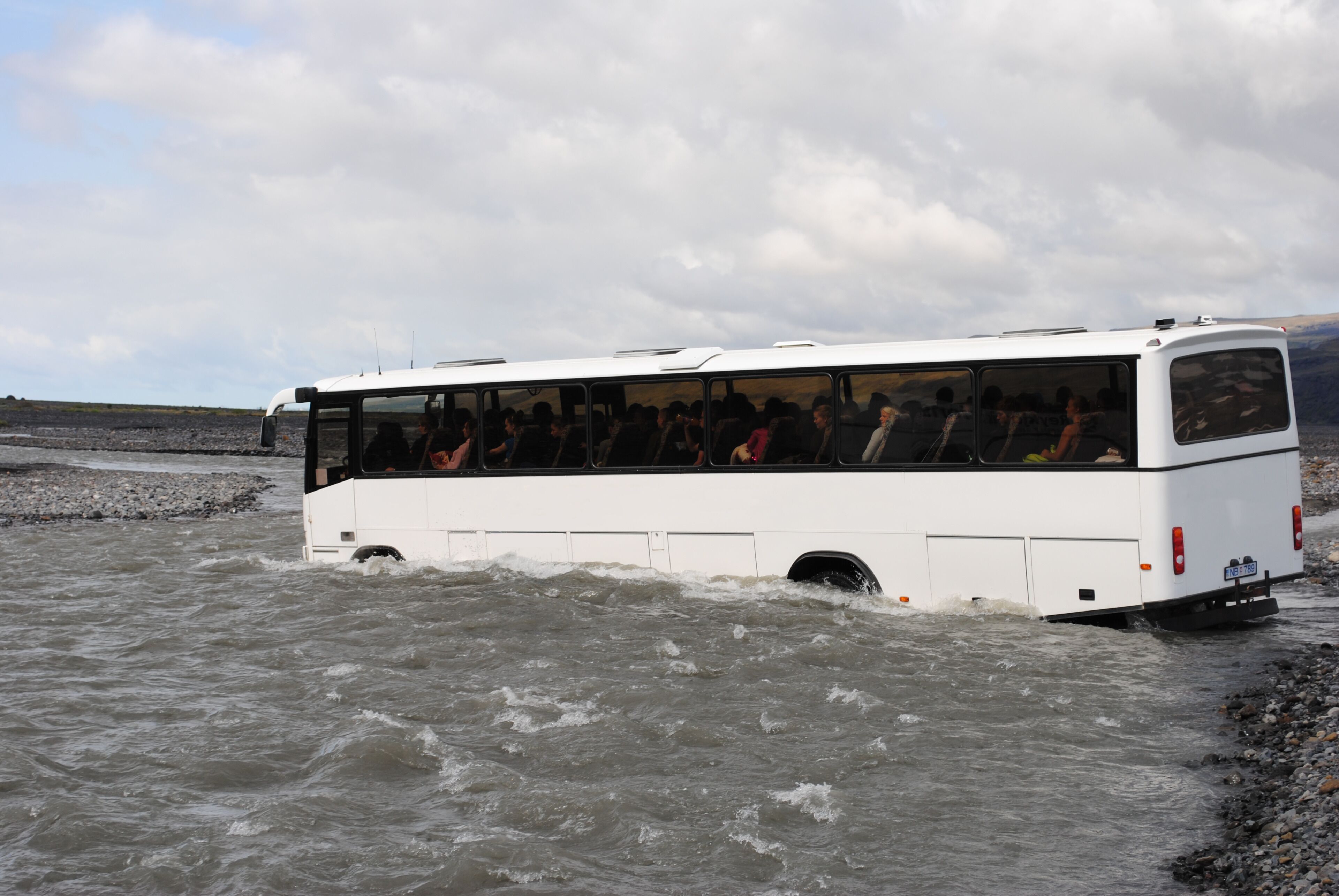 A white bus partially submerged in water.