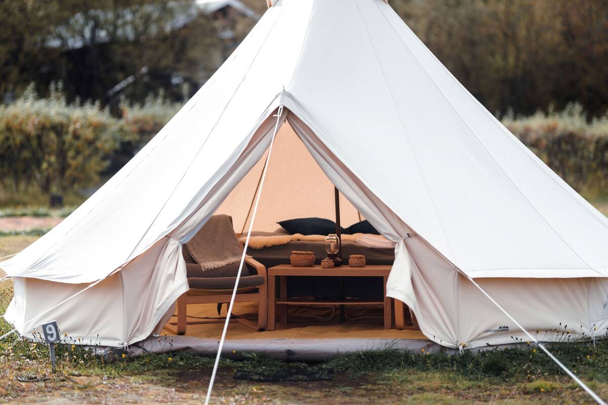 A tent with a bed, a table, and a chair inside.
