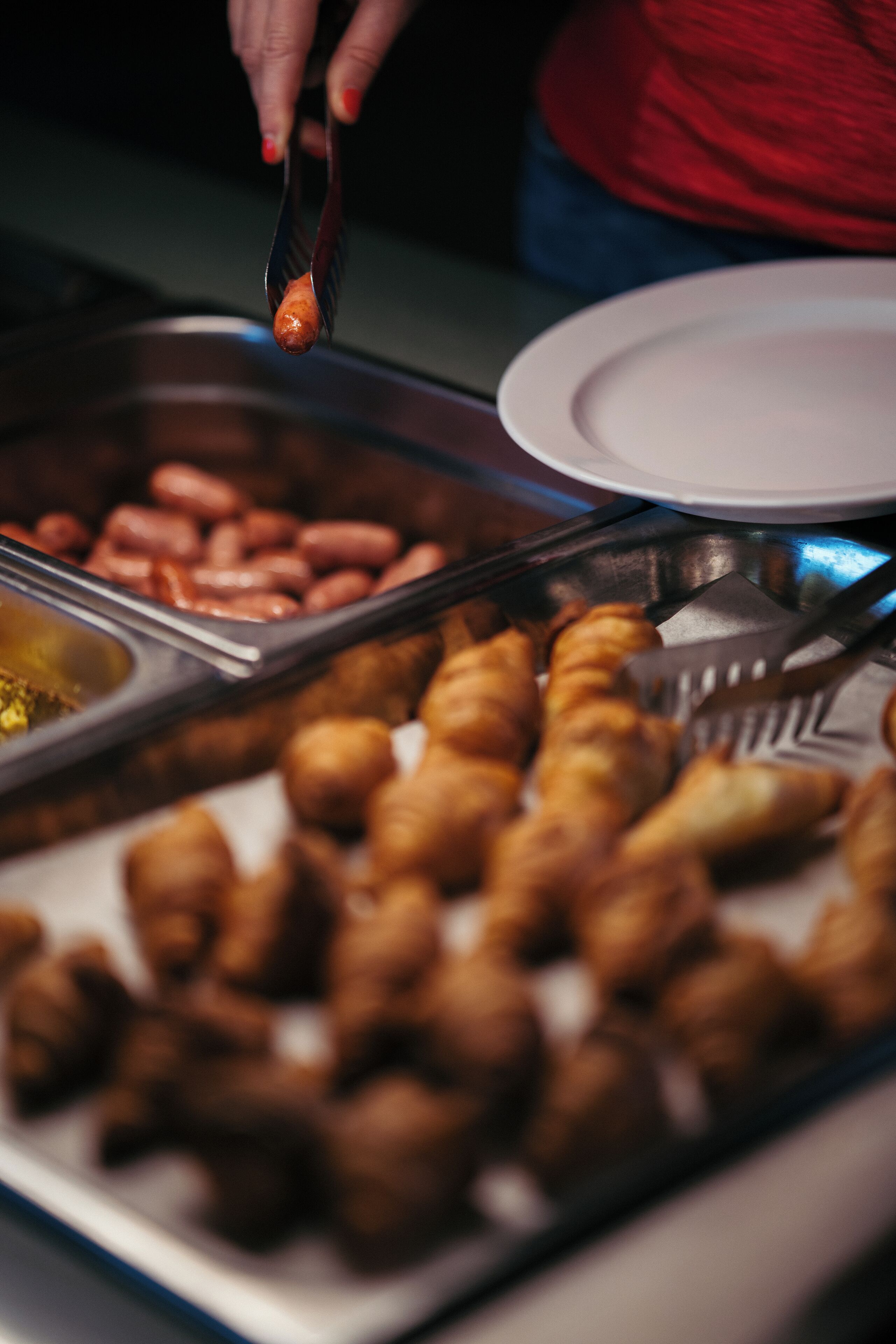 Buffet com diversos alimentos, incluindo salsichas e doces.
