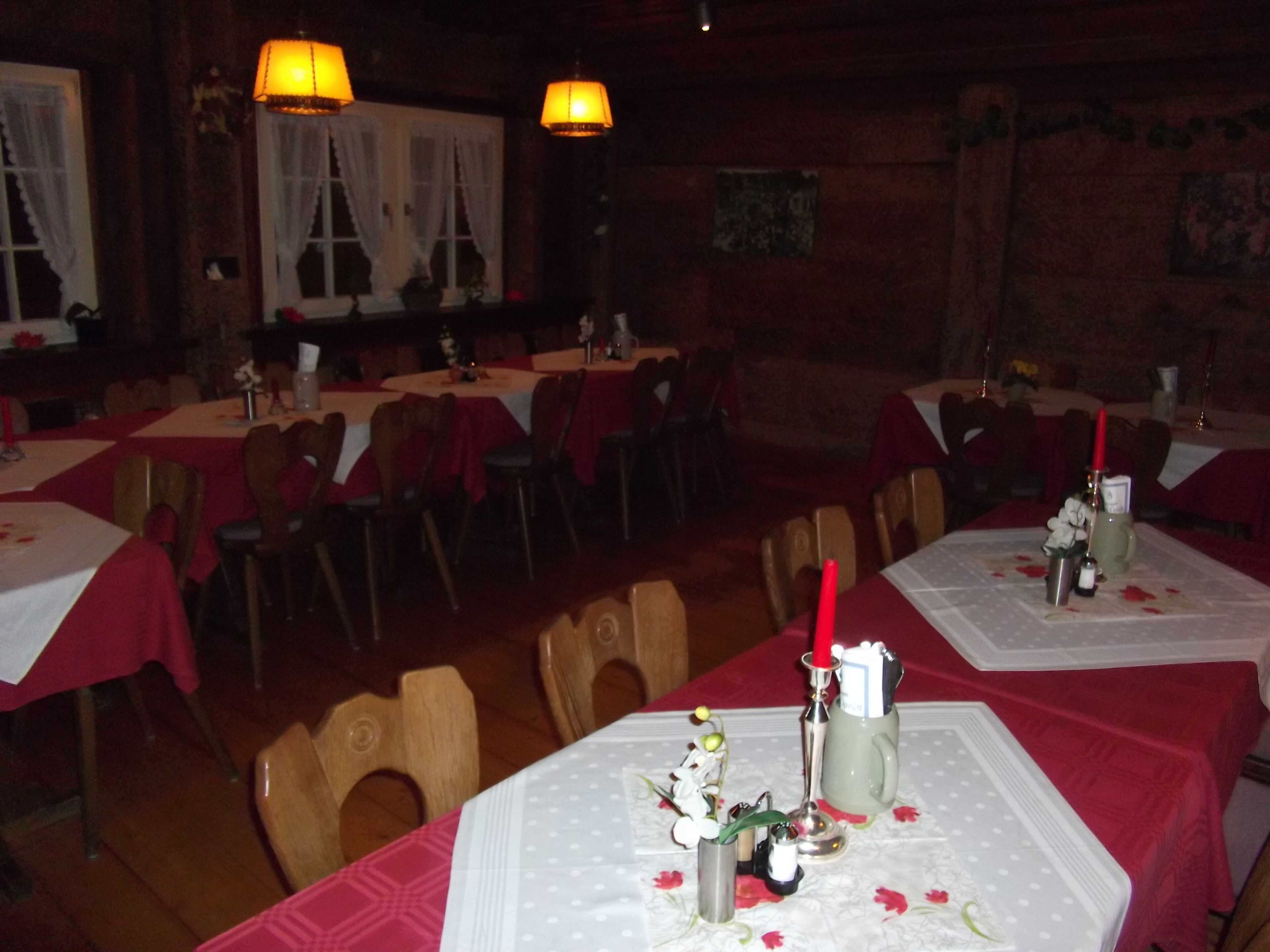 Een restaurant met meerdere tafels, elk voorzien van stoelen en rode tafelkleden.