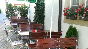 Outdoor seating with tables and chairs, green umbrellas, and potted plants. - Gasthof Stadtschänke (Grossbottwar)