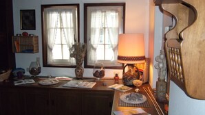 A cozy room with a wooden cabinet, a table with a lamp, and two windows with sheer curtains. - Gasthof Stadtschänke (Grossbottwar)