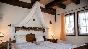 A bedroom with a wooden bed, a canopy, two bedside tables with lamps, and a window with curtains. - Gasthof Stadtschänke (Grossbottwar)