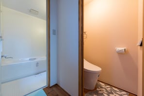 A bathroom with a bathtub, toilet, and a towel rack.