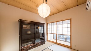 Une pièce de style japonais traditionnel, avec un sol recouvert de tatamis, une porte coulissante en papier de riz (shoji) et un buffet en bois foncé doté de portes en verre.
