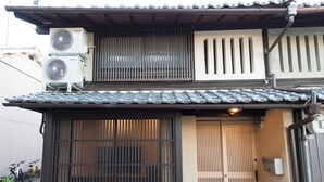 Un bâtiment japonais traditionnel, doté d’un toit recouvert de tuiles, de portes coulissantes et de climatiseurs.
