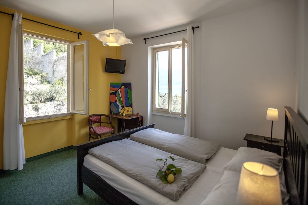 Habitación de hotel con dos camas, un escritorio, una silla, un televisor y una ventana con cortinas.