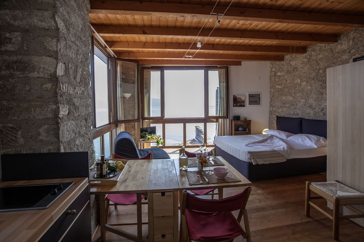 Una habitación acogedora con una mesa de madera, sillas, una cama y vistas al exterior.