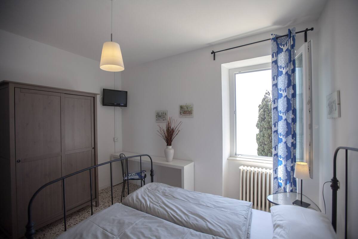 Un dormitorio con dos camas, un escritorio, un radiador y una ventana con cortinas.