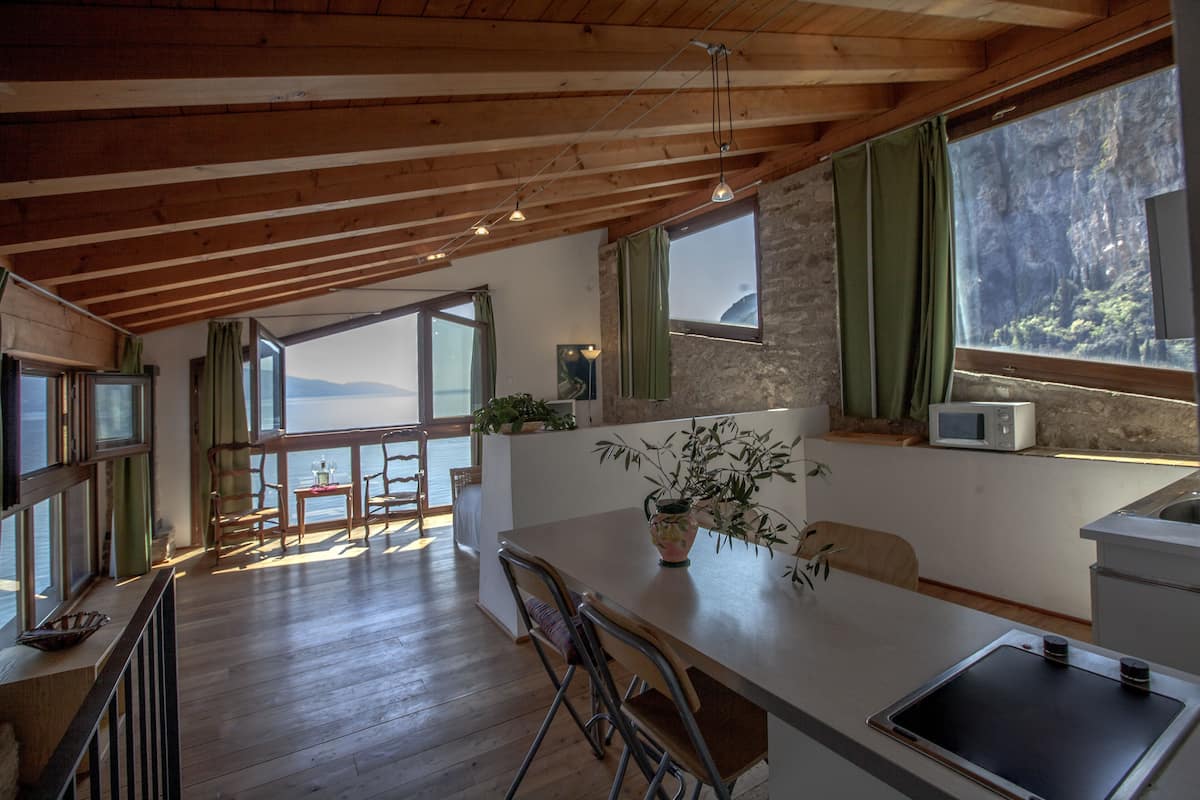 Una cocina amplia con vigas de madera, ventanas grandes y vista al mar.