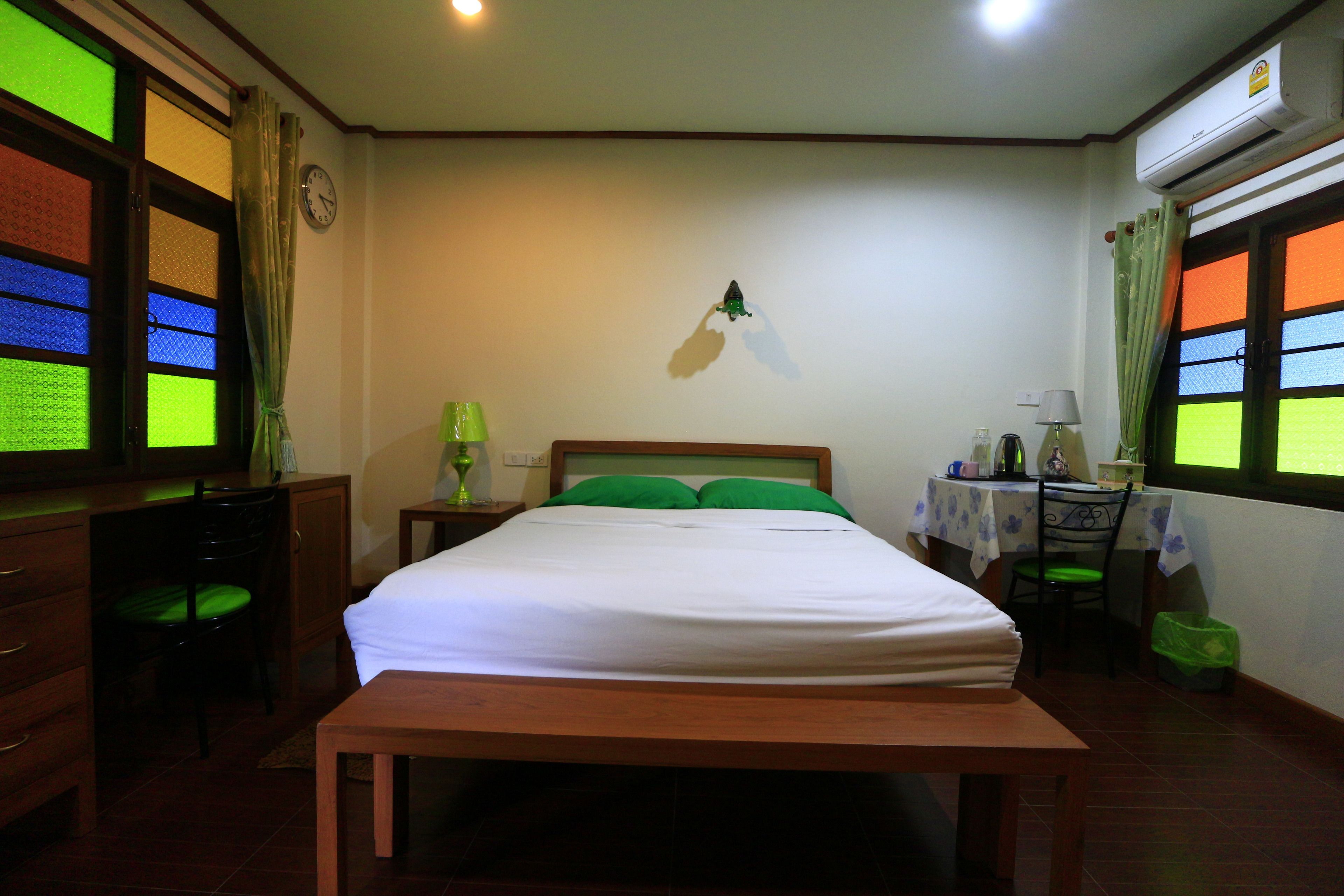 Un dormitorio con cama, escritorio, silla, mesa y aire acondicionado.