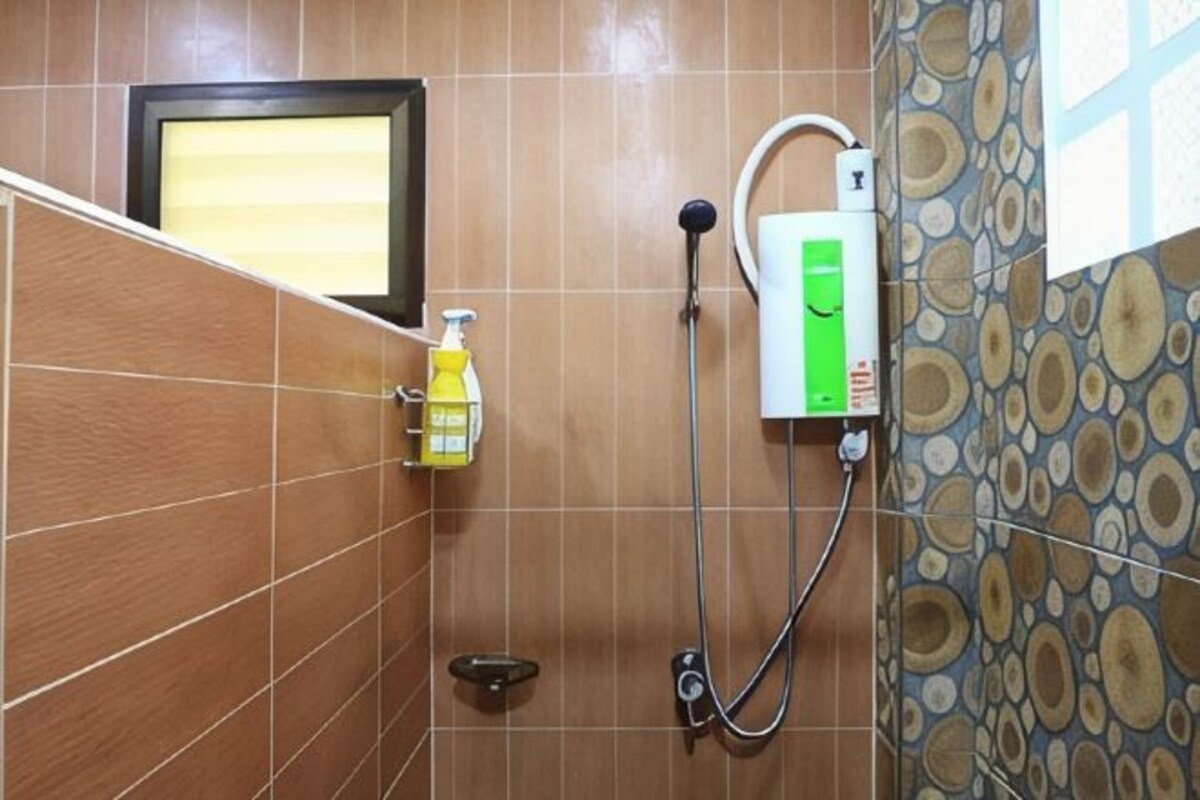 A bathroom with a shower, a hand soap dispenser, and a water heater.