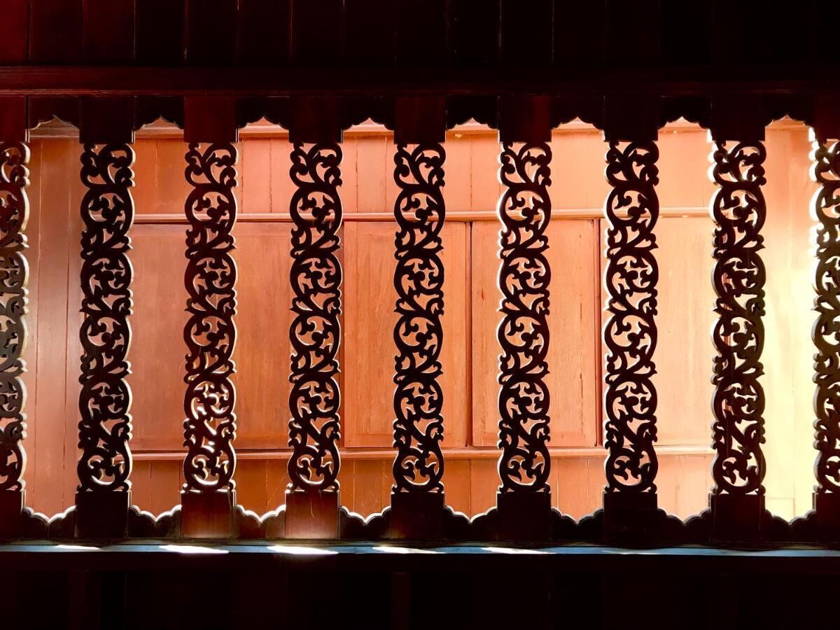 A row of ornate, dark-colored wooden panels with intricate carvings, likely part of a building's exterior.