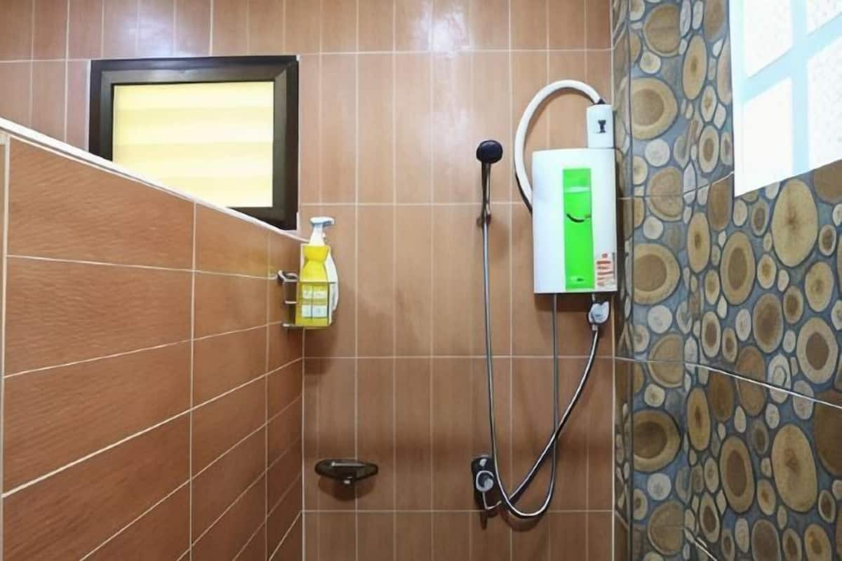 A bathroom with a shower, a hand soap dispenser, and a water heater.