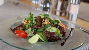 Une salade servie dans une assiette en verre, avec une fourchette à côté.