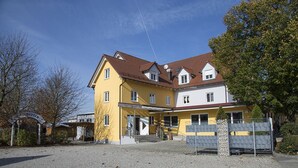 Un immeuble de deux étages avec une façade jaune et un toit rouge.