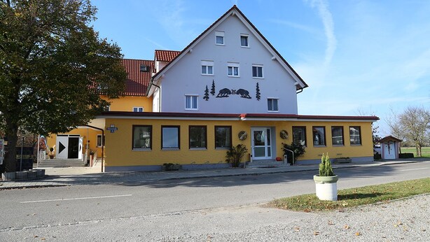 A two-story building with a yellow facade and a red roof. - Zu Müllers Winkelhausen (Langenmosen)