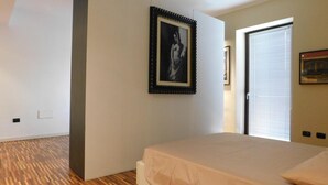 A bedroom with a bed, a framed picture on the wall, and a door. - Garden Apartment (Verona)