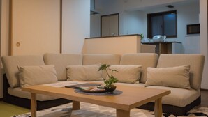 A modern living room with a sofa, a wooden coffee table, and a potted plant.