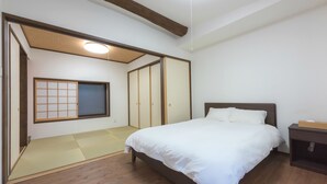A bedroom with a bed, a nightstand, a wardrobe, and a shoji screen.