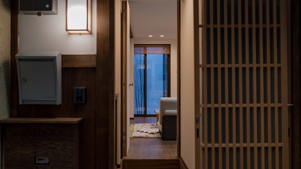 A hallway leading to a room with a sliding door, a small rug, and a chair.
