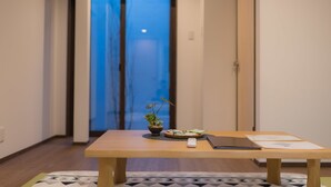A hallway with a wooden table, a potted plant, a remote control, and a tablet.