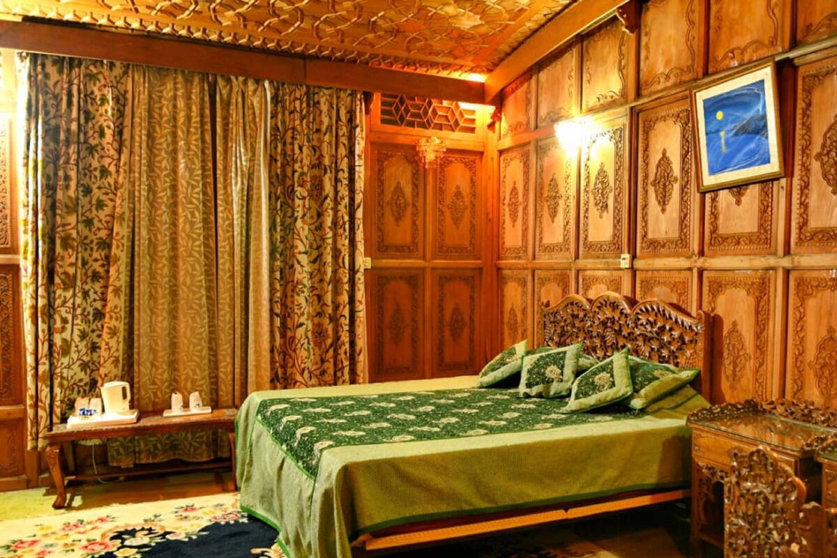 A room with a bed, a nightstand, a dresser, and a wall with a framed picture.