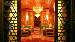 An ornate room with intricate wall carvings, a central chandelier, and traditional furnishings. - De-Laila Houseboats (Srinagar)