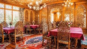 An ornately decorated room with intricate woodwork, a chandelier, and a patterned rug. - De-Laila Houseboats (Srinagar)