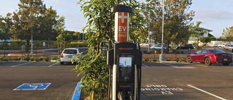 Un estacionamiento con una estación de carga identificada como 'EV ONLY' y un espacio reservado para discapacitados, de color azul.