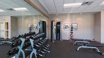 A gym with weightlifting equipment, mirrors, and exercise balls.