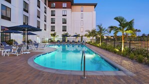A hotel pool area with lounge chairs and umbrellas, surrounded by palm trees and a brick walkway. - TownePlace Suites by Marriott San Diego Airport/Liberty Station (San Diego)