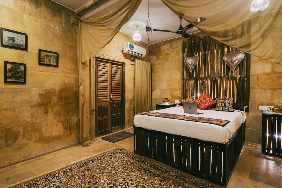 Quarto com uma cama grande, um ventilador de teto e um ar condicionado fixado na parede.
