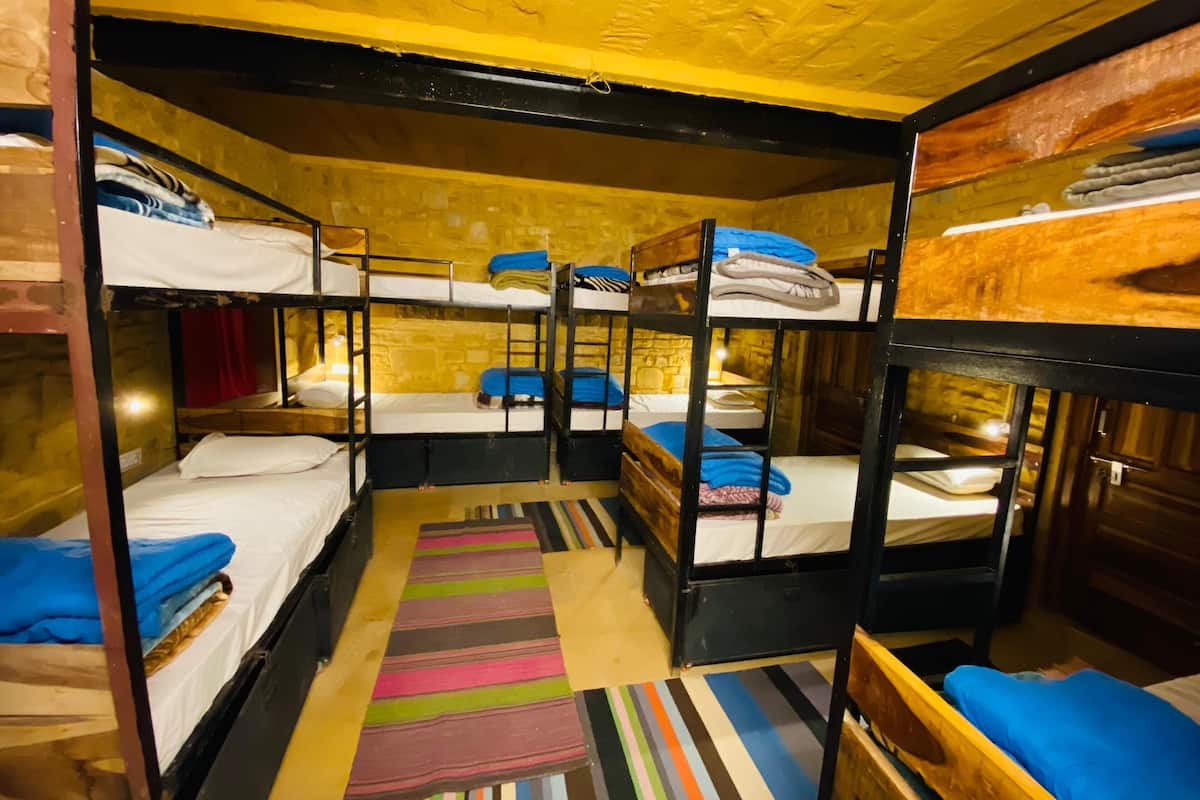 Quarto com beliches, tapete listrado e teto de madeira.
