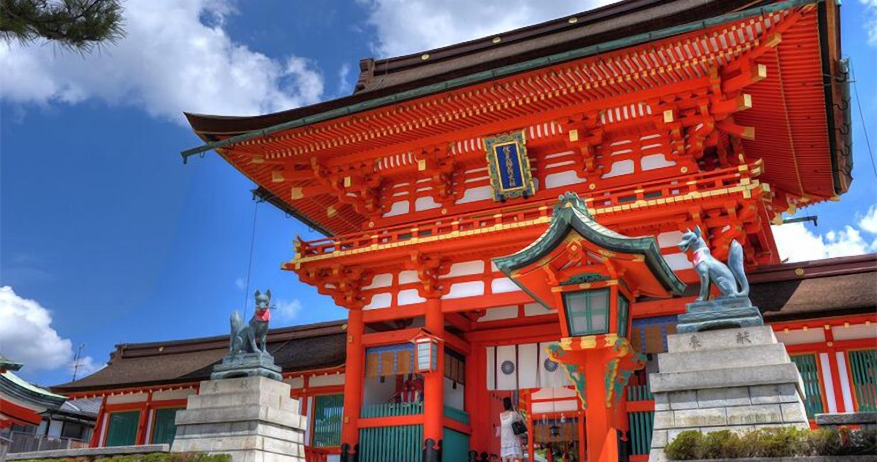 Un edificio japonés tradicional con una decoración roja y verde, una entrada destacada y estatuas.